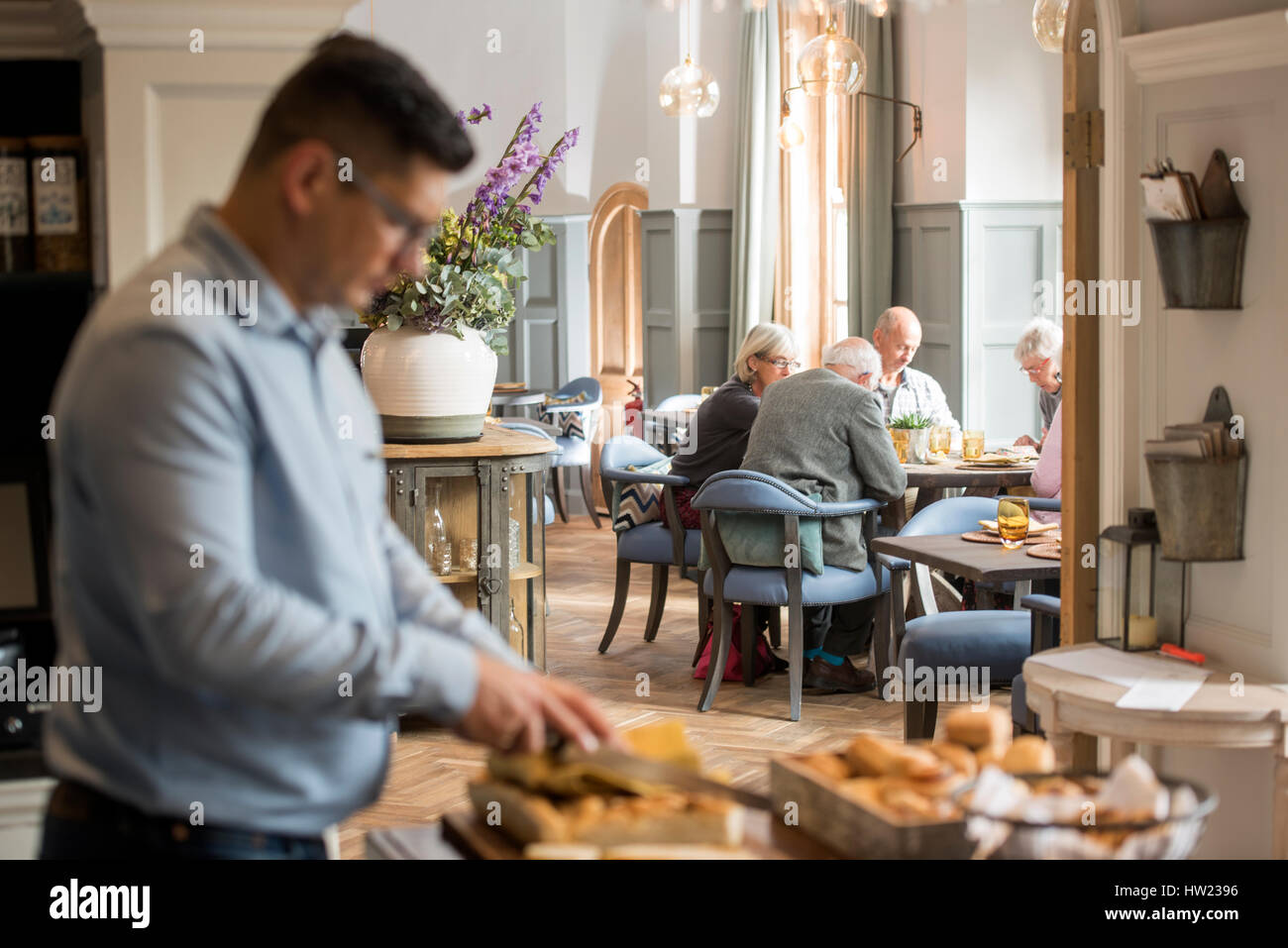 Le maître d'hôtel la préparation de pain, tandis qu'un groupe de retraités ont déjeuné au Painswick, près de Stroud, Gloucestershire UK Banque D'Images