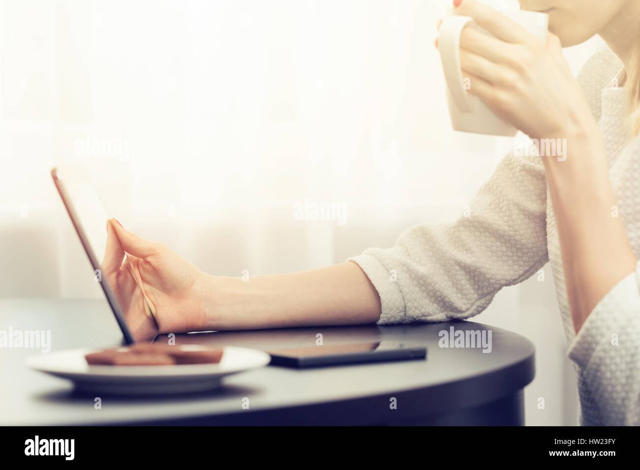 Femme buvant du café et using digital tablet Banque D'Images