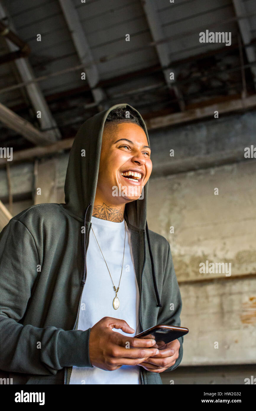 Androgyne rire Mixed Race woman texting on cell phone Banque D'Images