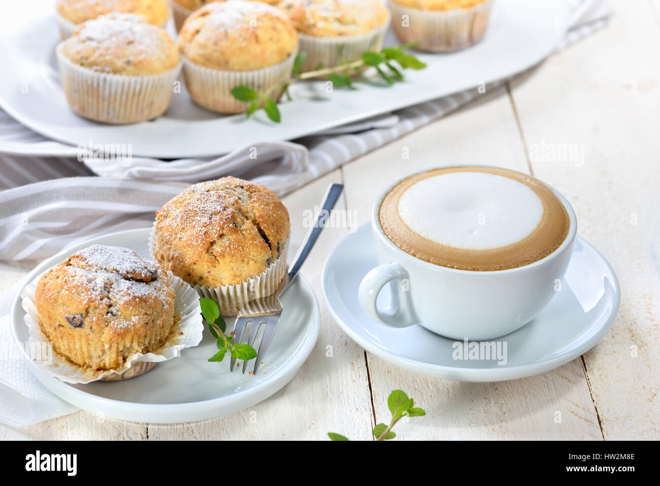 Muffins à la banane au chocolat sortant du four de sucre glace servi avec une tasse de cappuccino Banque D'Images