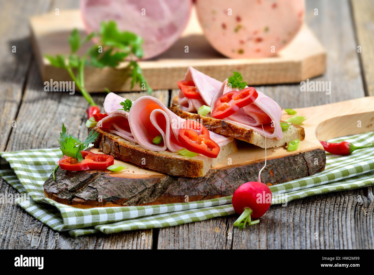 Tranches de saucisse Bavaroise sur pain de campagne, garni et servi sur une planche en bois rustique Banque D'Images