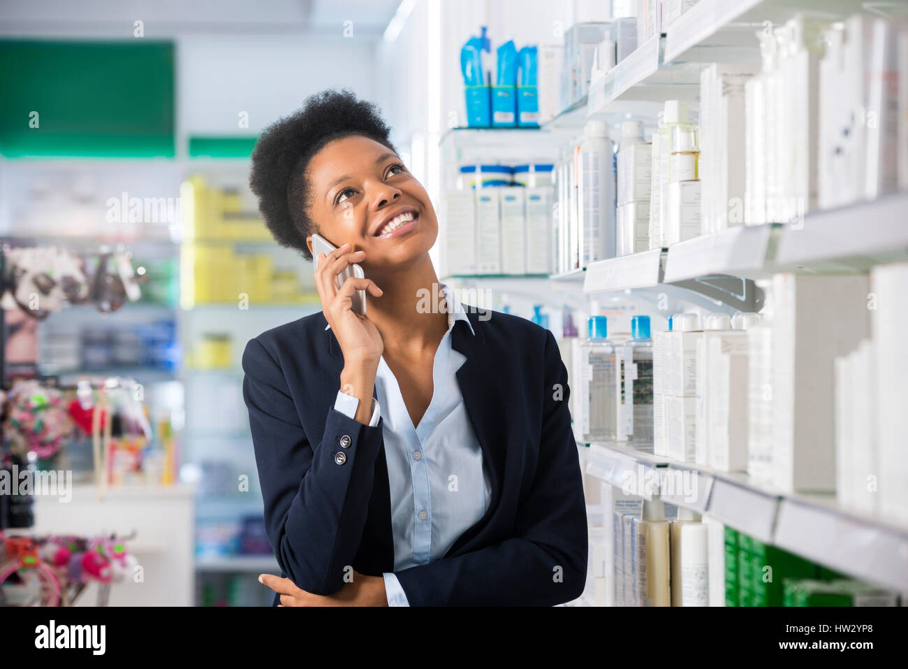 Smiling young businesswoman using mobile phone in pharmacy Banque D'Images