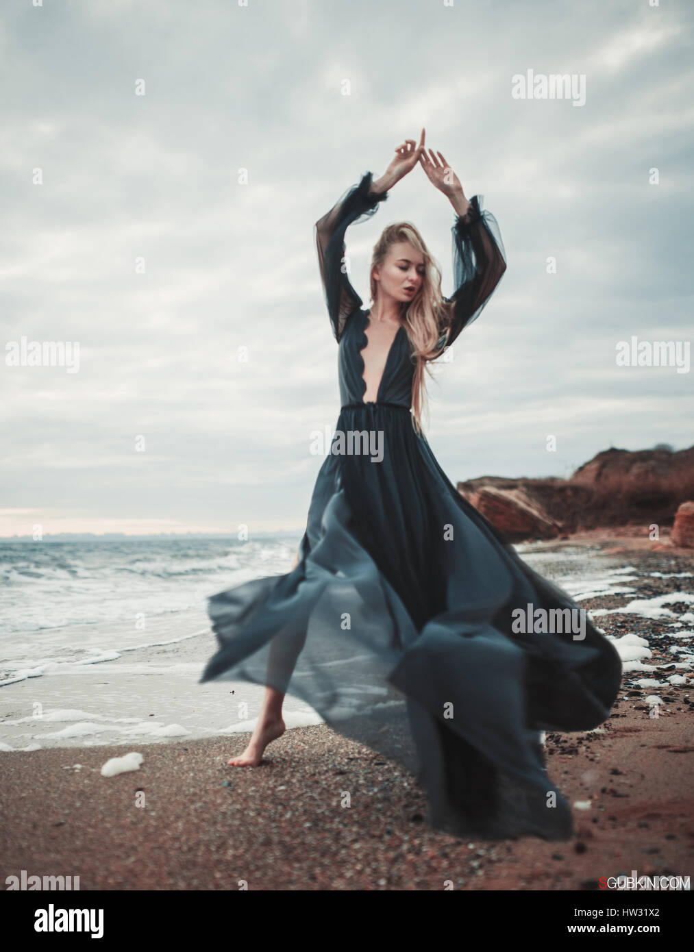 Jeune Femme En Robe Noire Transparente Longue Entre La Plage