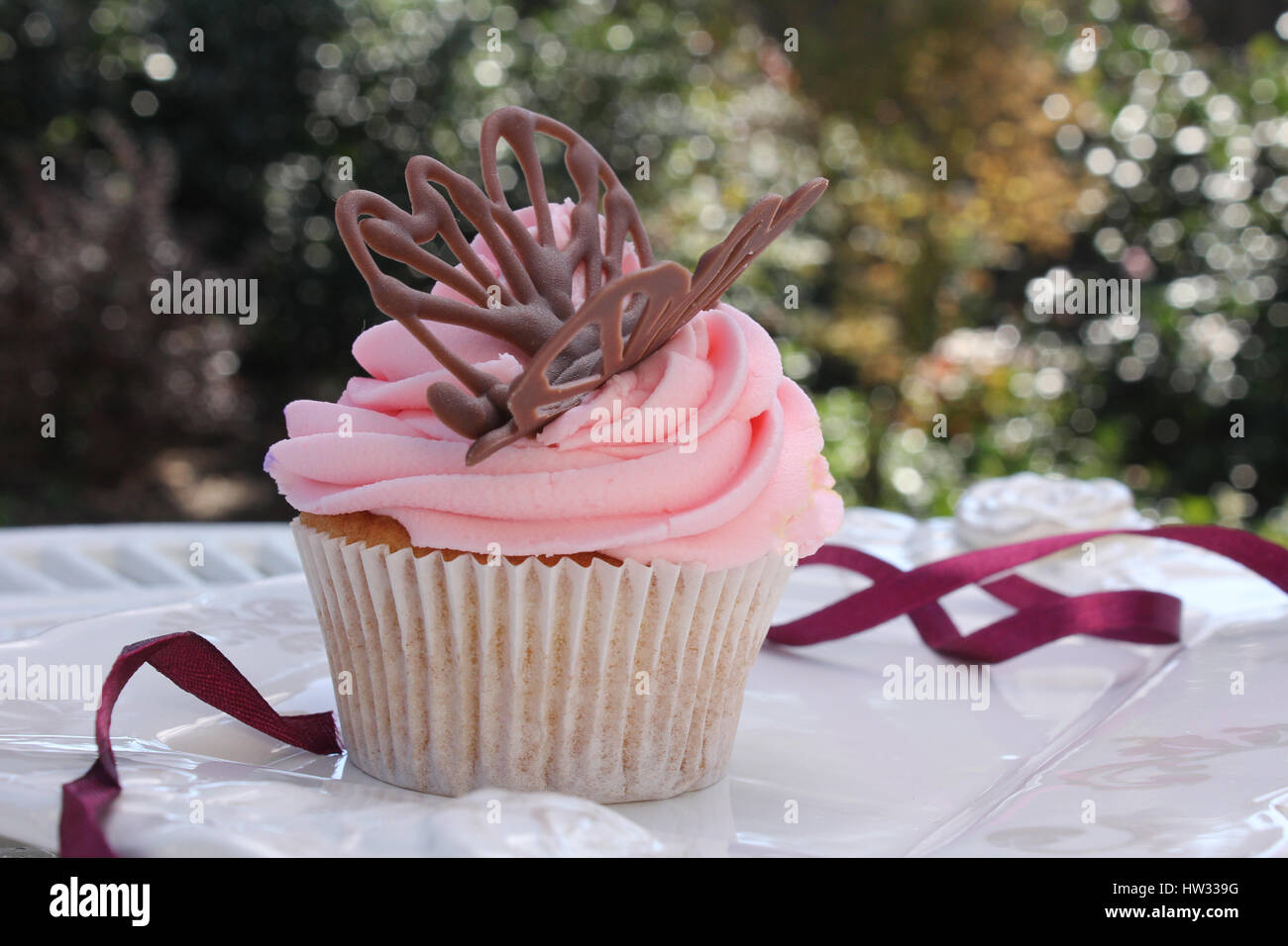 Un fait biologique, frais, vanille Glace fraise cupcake dans de doux tons de rose avec une touche de violet et d'un délicieux glaçage décoration sur le chocolatebutterfly Banque D'Images