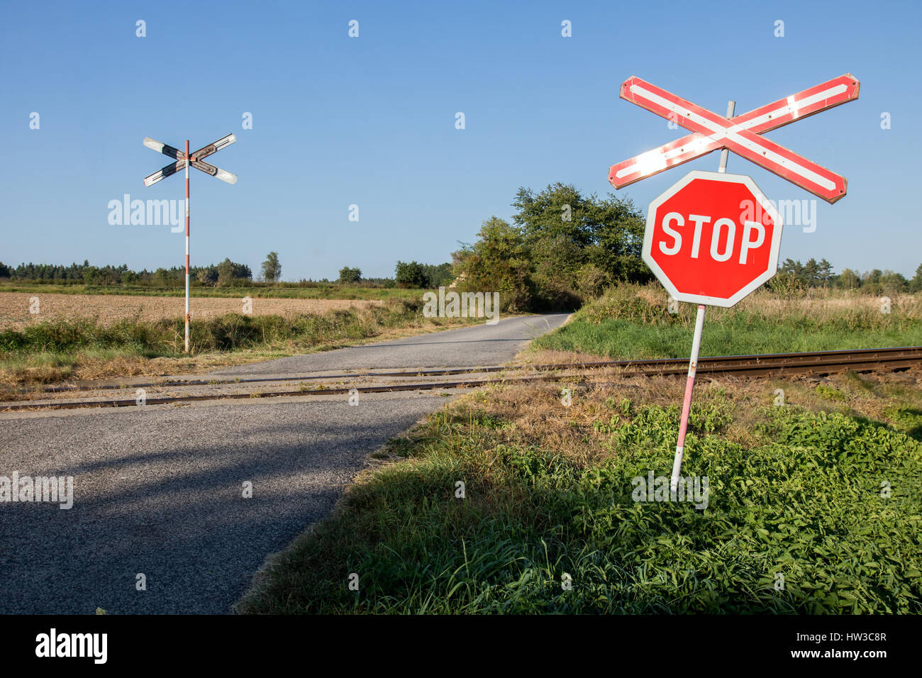 Railroad crossing warning sign. Une ancienne voie ferrée signer près d'une voie ferrée. Les voies de chemin de fer avec panneau de circulation dans une scène rurale. Banque D'Images