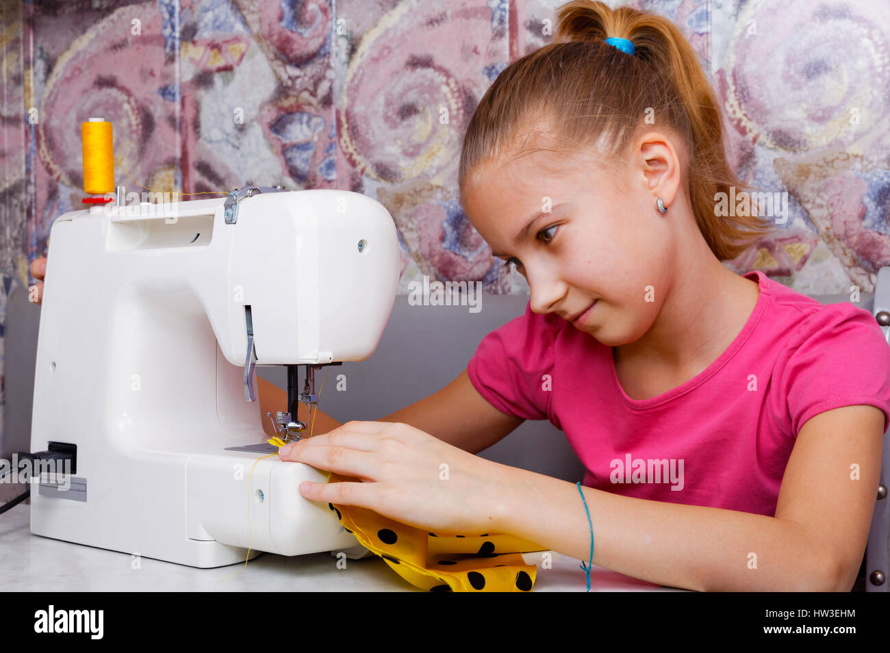 Fille apprend à coudre sur une machine à coudre électrique Banque D'Images