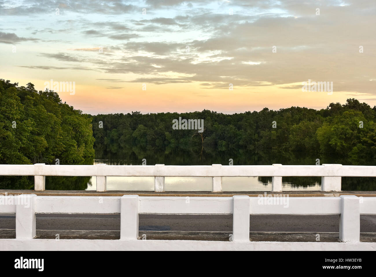 Vue latérale du pont au-dessus d'une rivière bordée d'arbres comme miroir à un coucher de soleil spectaculaire. Banque D'Images