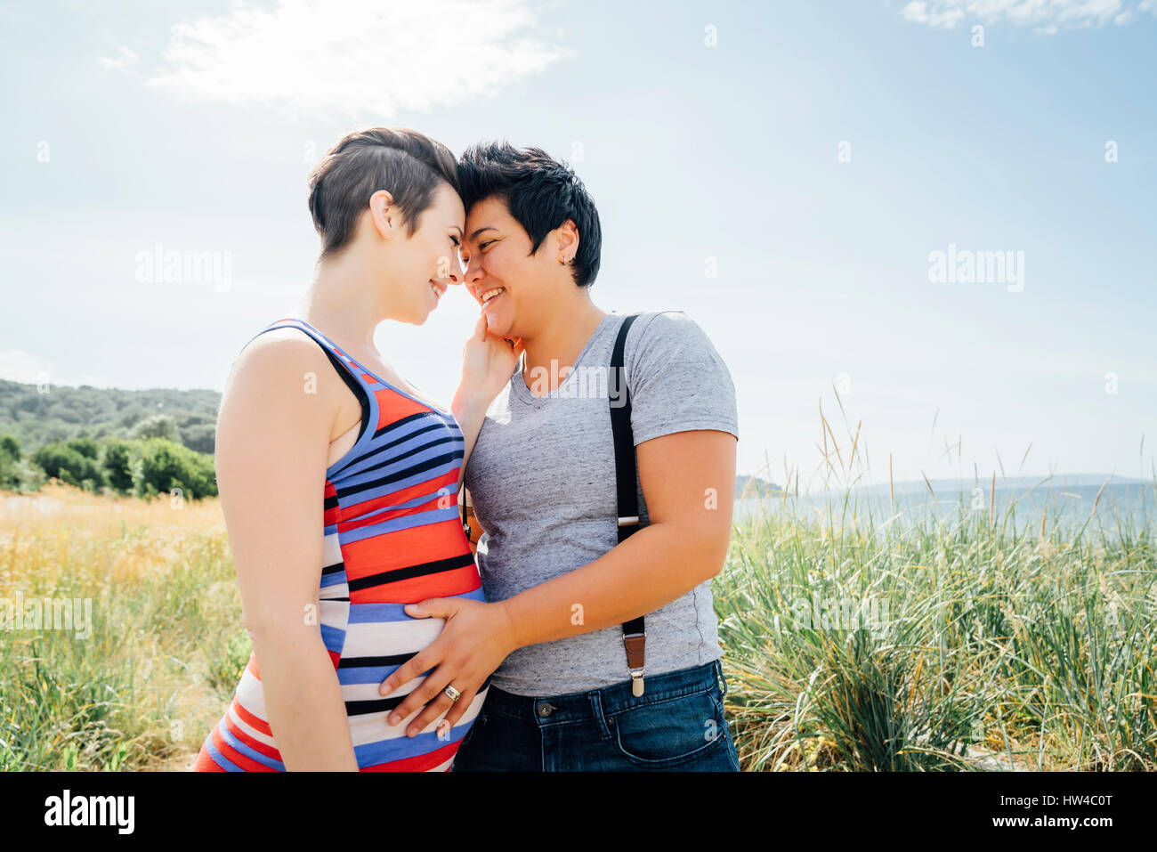 Lesbiennes enceintes couple hugging outdoors Banque D'Images