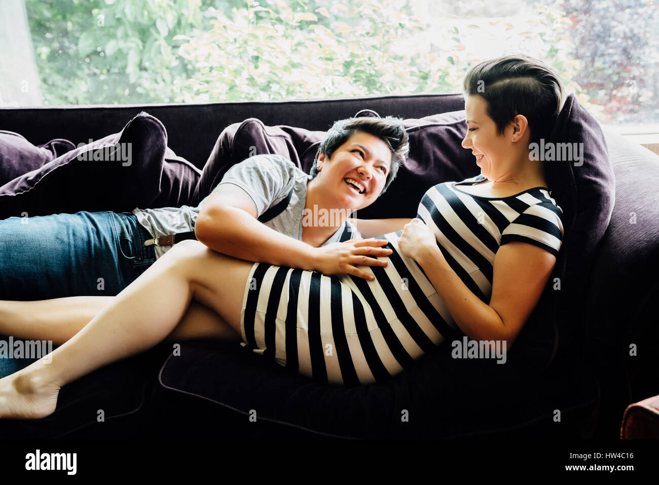 Couple de lesbiennes enceintes câlins sur canapé Banque D'Images