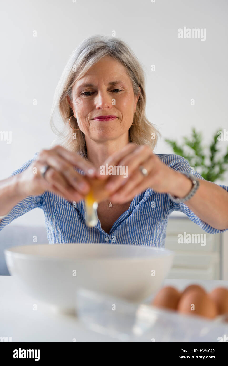 Caucasian woman cracking oeuf dans bol Banque D'Images