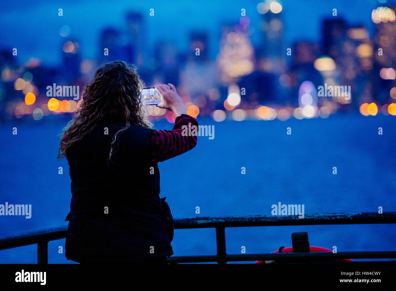 Caucasian woman on voile photographier waterfront urbain avec cell phone Banque D'Images