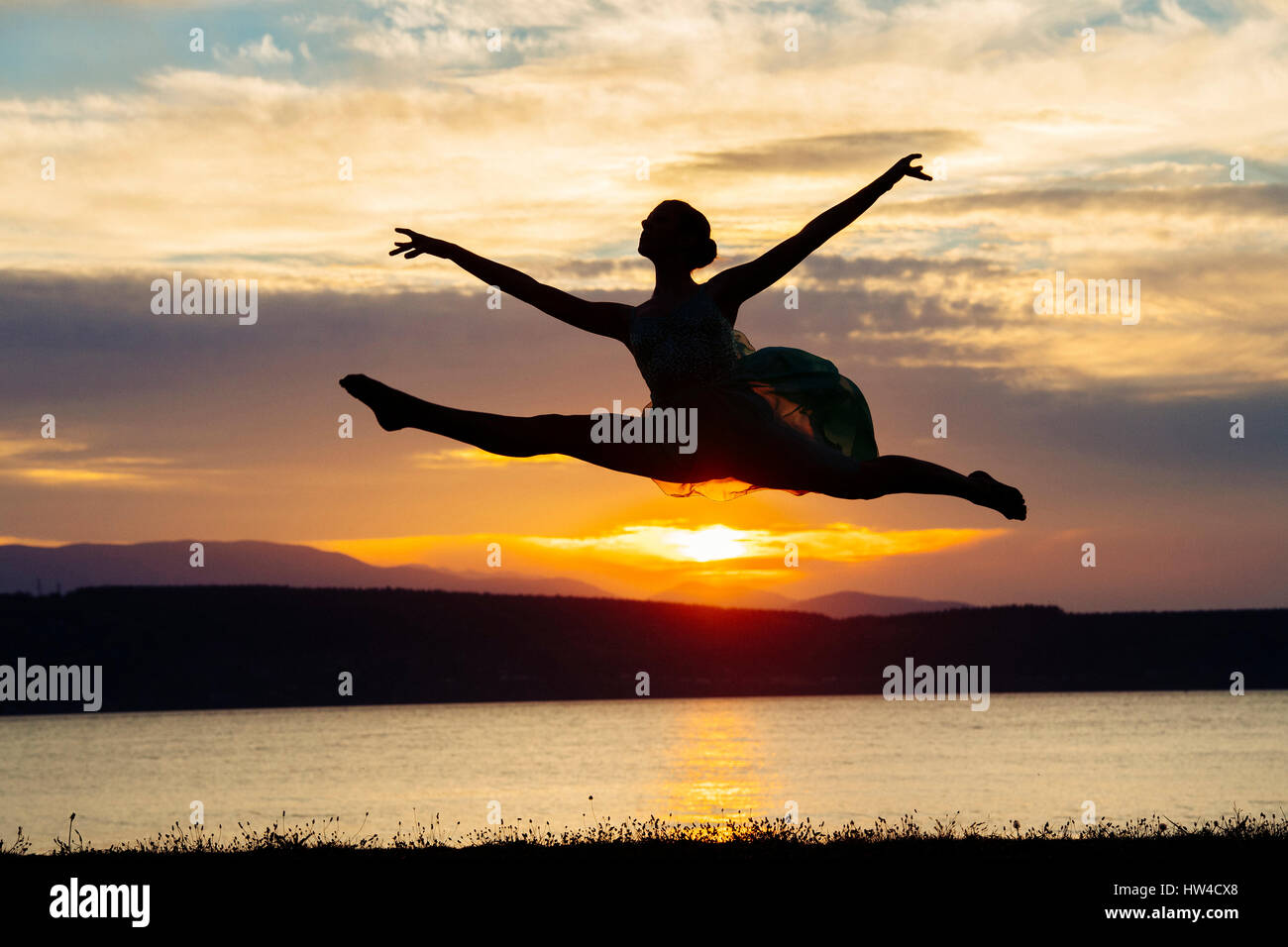 Caucasian ballerina jumping on beach at sunset Banque D'Images