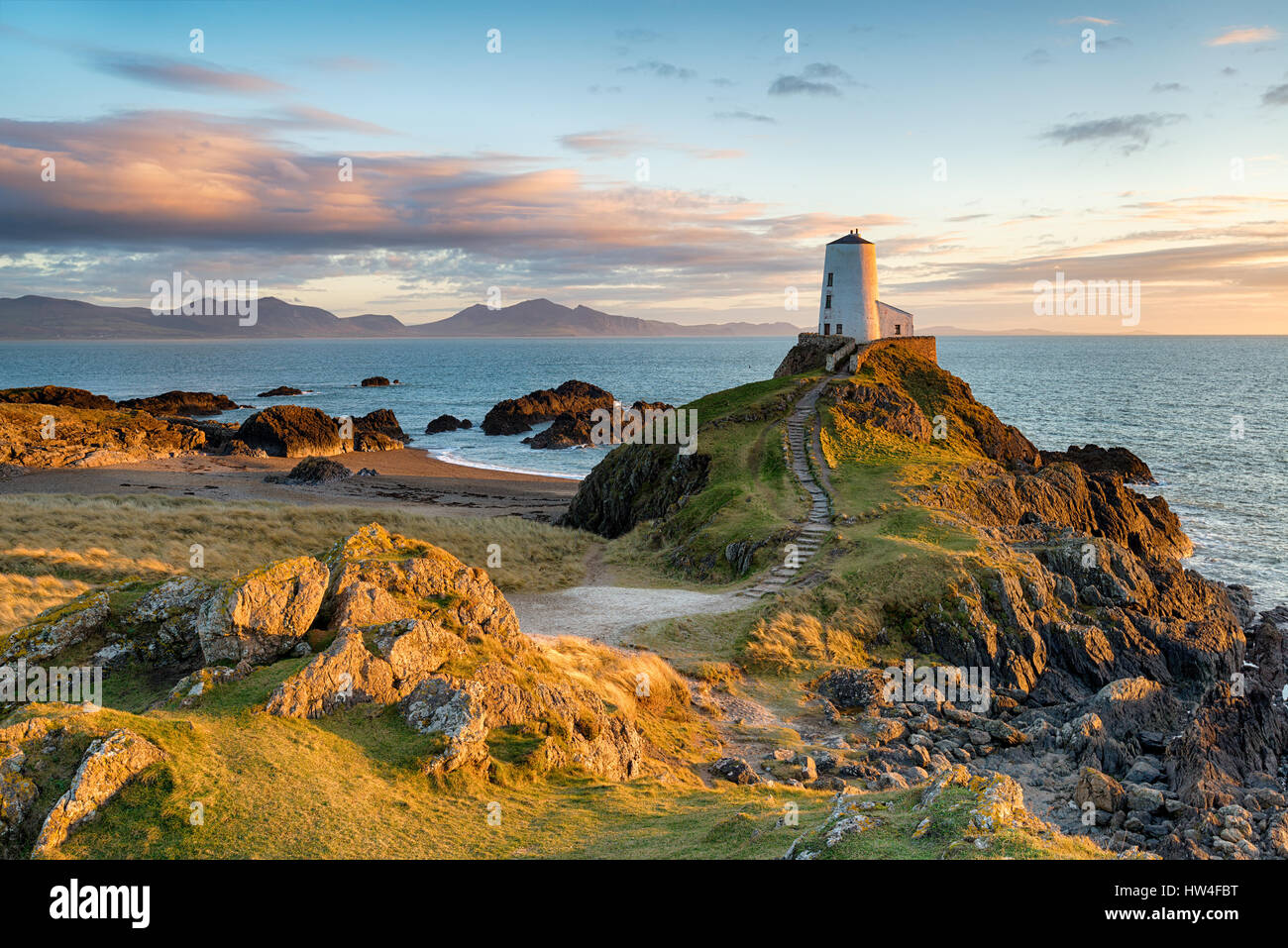 Coucher du soleil à Ynys Llanddwyn île sur la côte d'Anglesey en Galles du Nord avec les montagnes de Snowdonia au loin. Banque D'Images