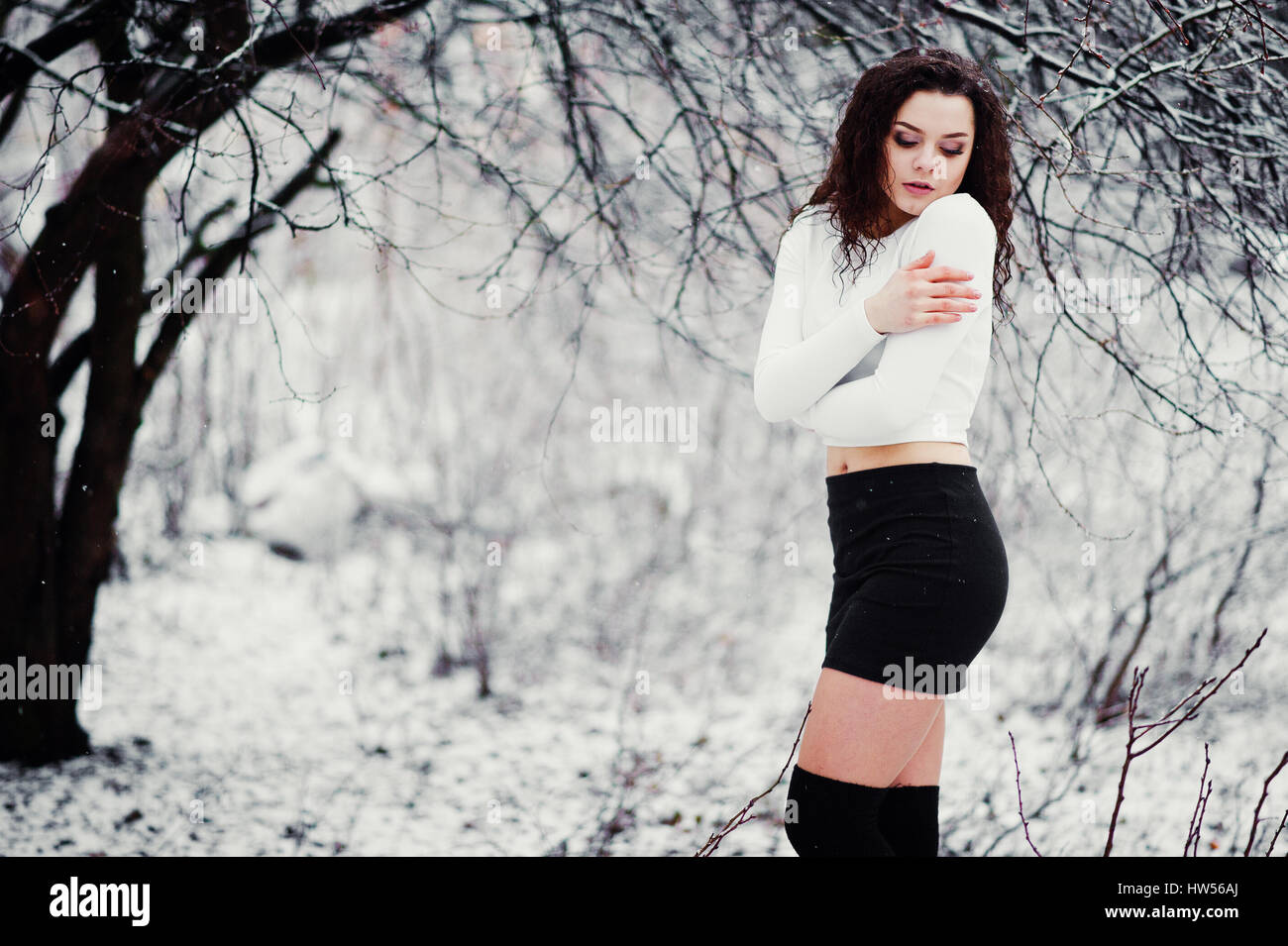 Fille brune frisée contexte de chute de neige, de l'usure sur black mini  jupe et des bas de laine. Sur le modèle de l'hiver. Fashion portrait au  temps de neige. Instagra Photo