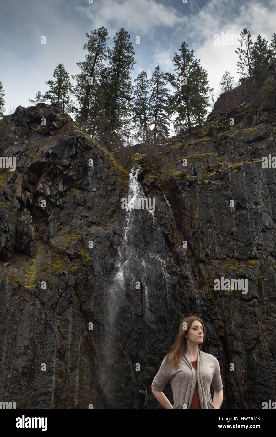 Une femme se tenir sous une cascade, dans le Montana. Banque D'Images