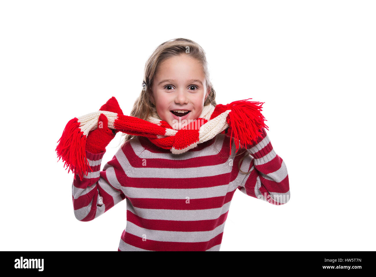 Cute little girl joyeux chandail tricoté, écharpe et mitaines isolé sur fond blanc. Les vêtements d'hiver Banque D'Images