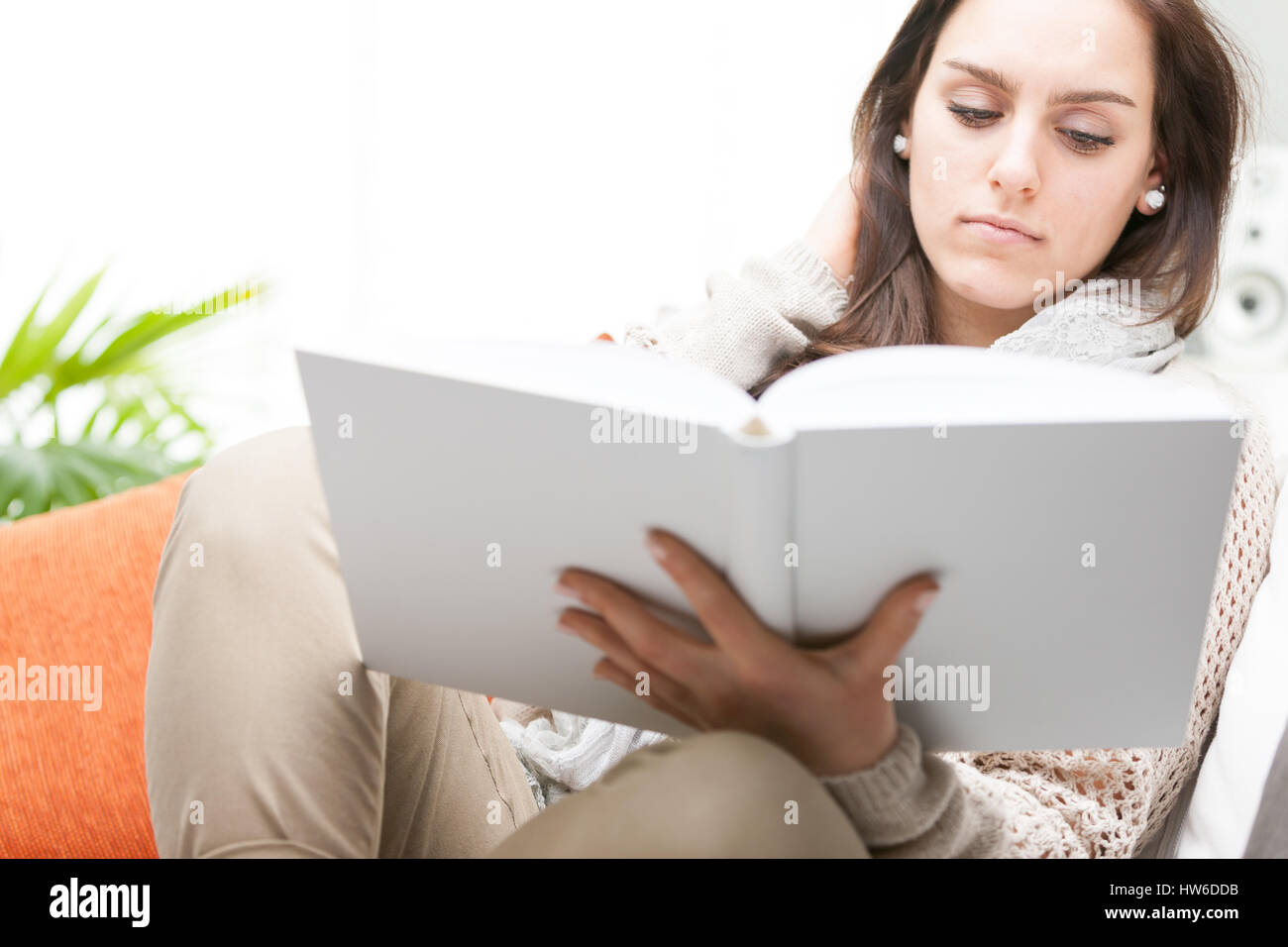 Belle Jeune femme lisant un livre relié pour les loisirs ou d'études avec une grave expression grossoyée, Close up sur le livre Banque D'Images