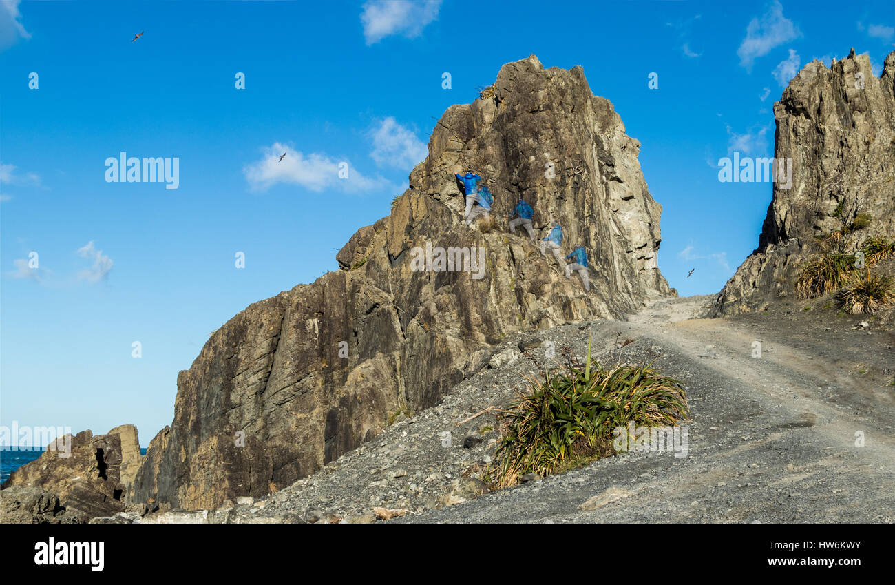 Man climbing up porte Devils rock, Te Kopahou réserver, sur la côte sud de la Nouvelle-Zélande. Banque D'Images