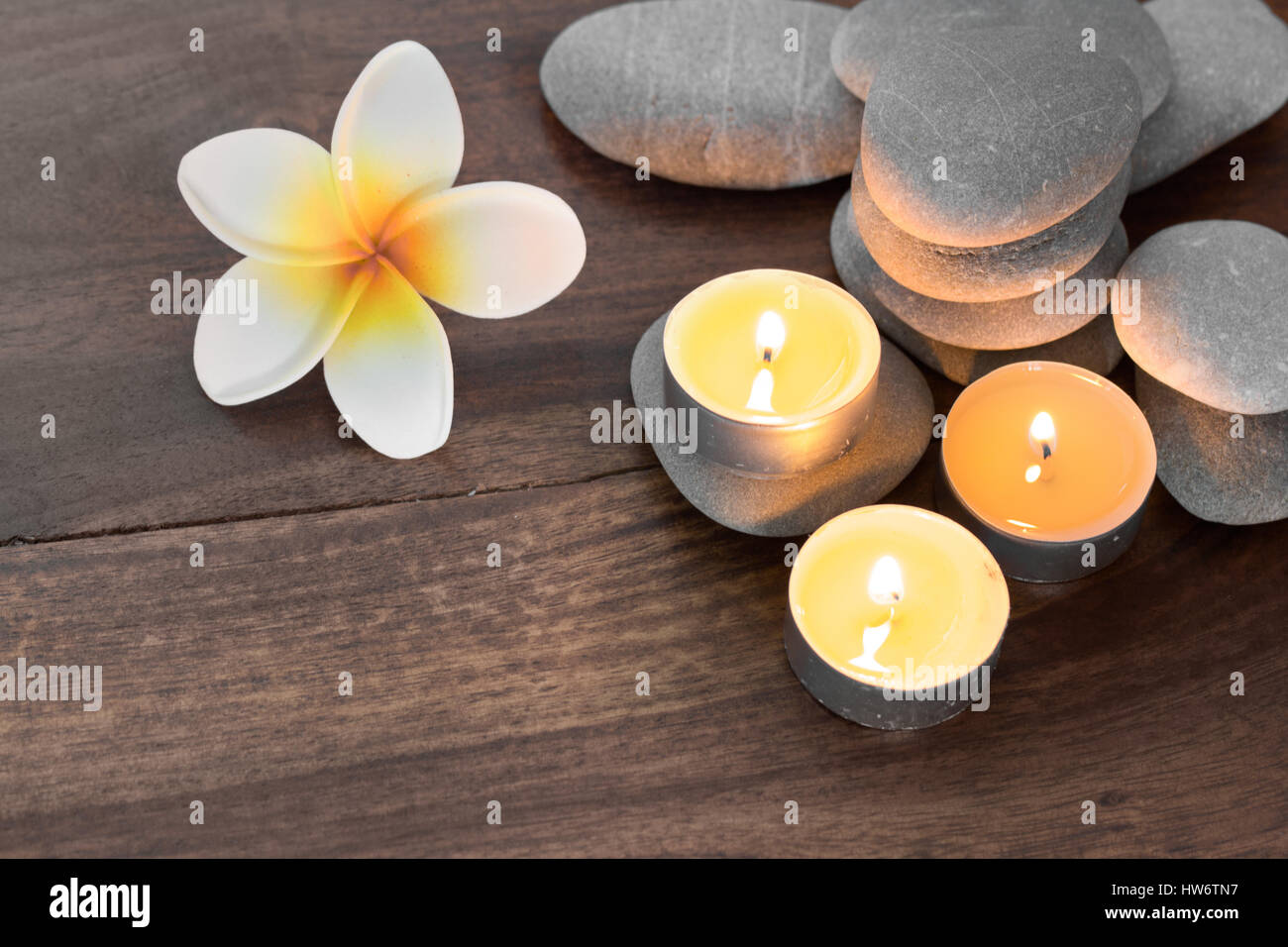 Composition spa avec des bougies pierres et fleurs sur table en bois Banque D'Images