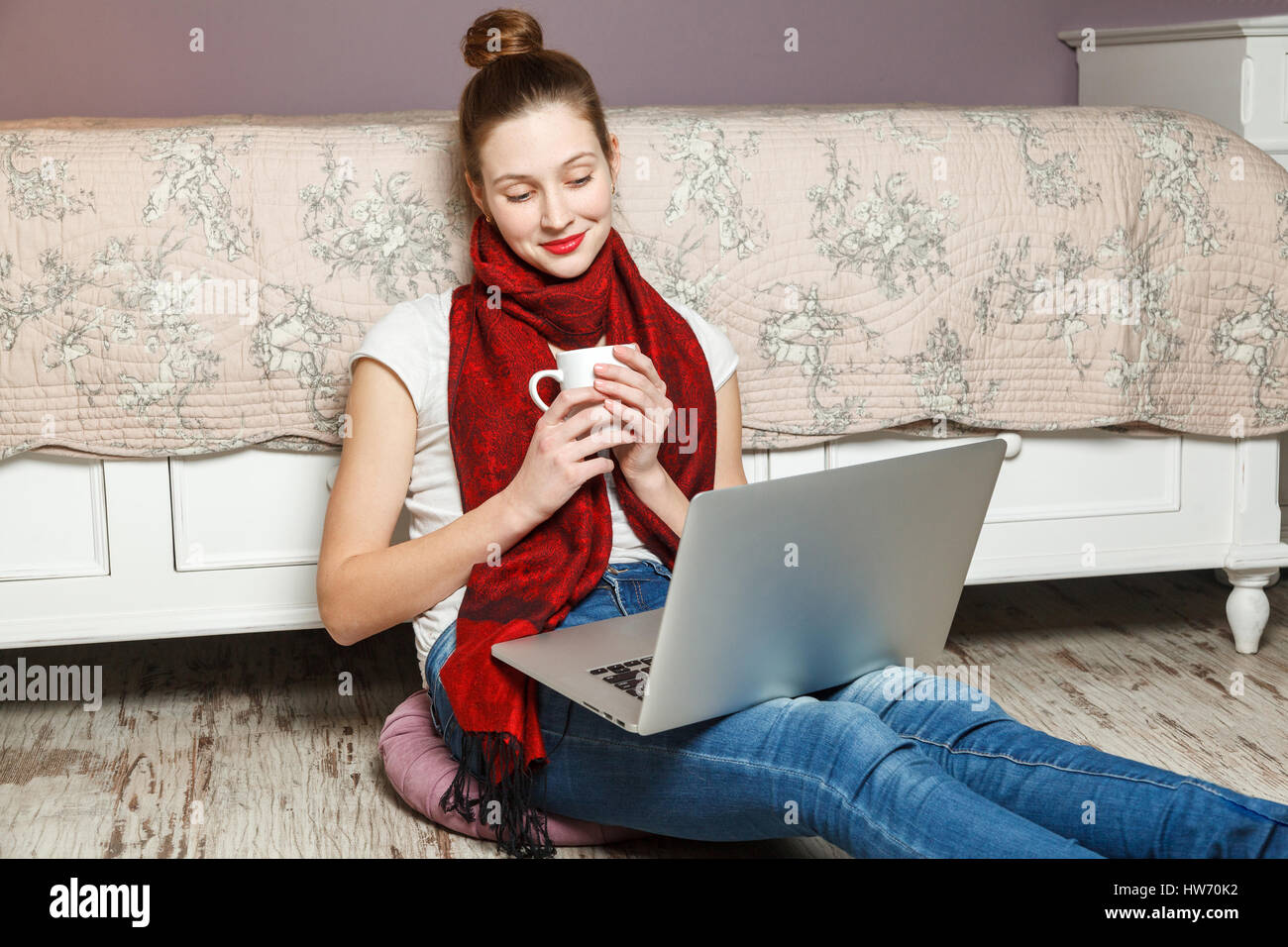 Femme d'Ecommerce. Jeune femme à l'aide d'ordinateur pour faire des achats en ligne, assis sur le plancher et de boire du café. Banque D'Images