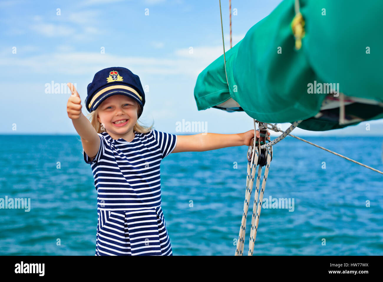Petit bébé heureux le capitaine à bord du yacht à regarder la mer au large de l'été sur une croisière. Voyage d'aventure, le yachting avec enfant en vacances en famille. Banque D'Images
