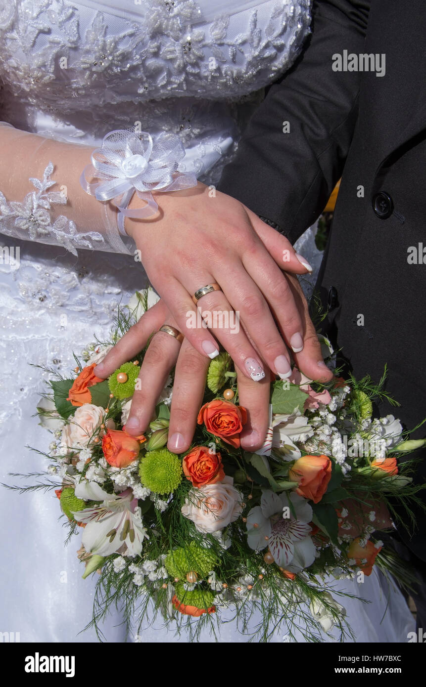 Mains de jeunes mariés, les anneaux de mariage et bouquet de mariage. Banque D'Images