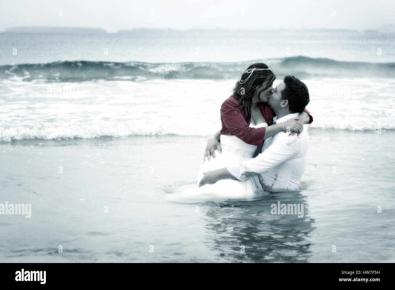 Couple marié jouant dans l'eau de mer Banque D'Images