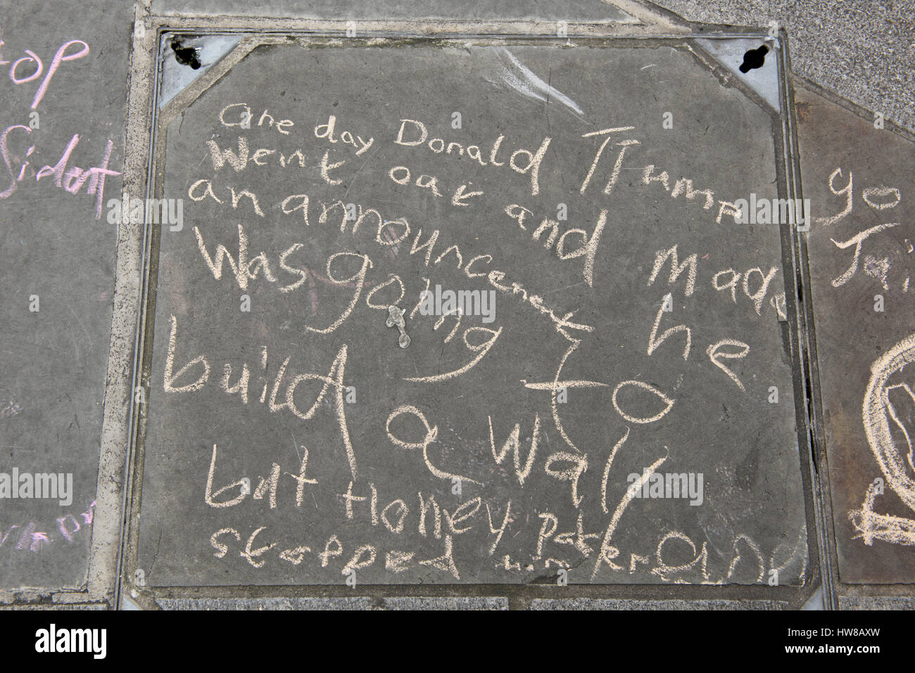 Anti-Trump et anti-racisme de message sur la 'Donald Trump va construire un mur' est écrit sur la chaussée par un enfant manifestant Banque D'Images