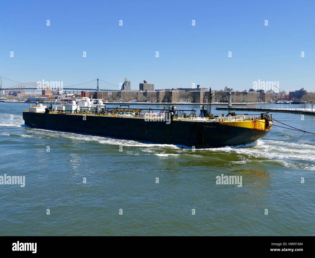 Barge commerciale passant Roosevelt Island Lighthouse avec pont RFK en arrière-plan. East River, New York City, New York, USA Banque D'Images