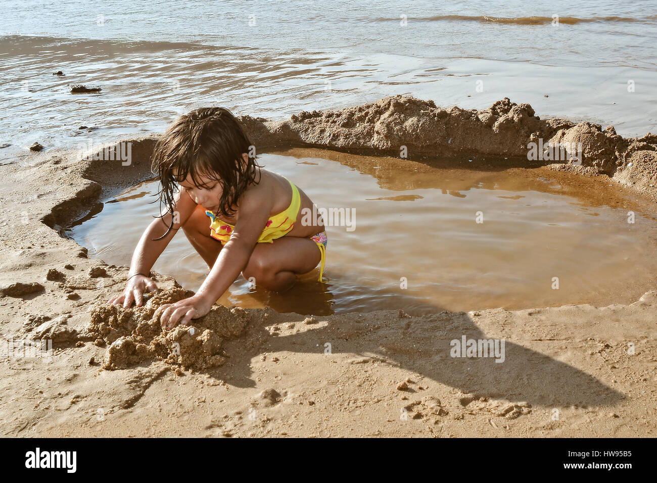 Petite fille jouant avec le sable sur la plage Banque D'Images