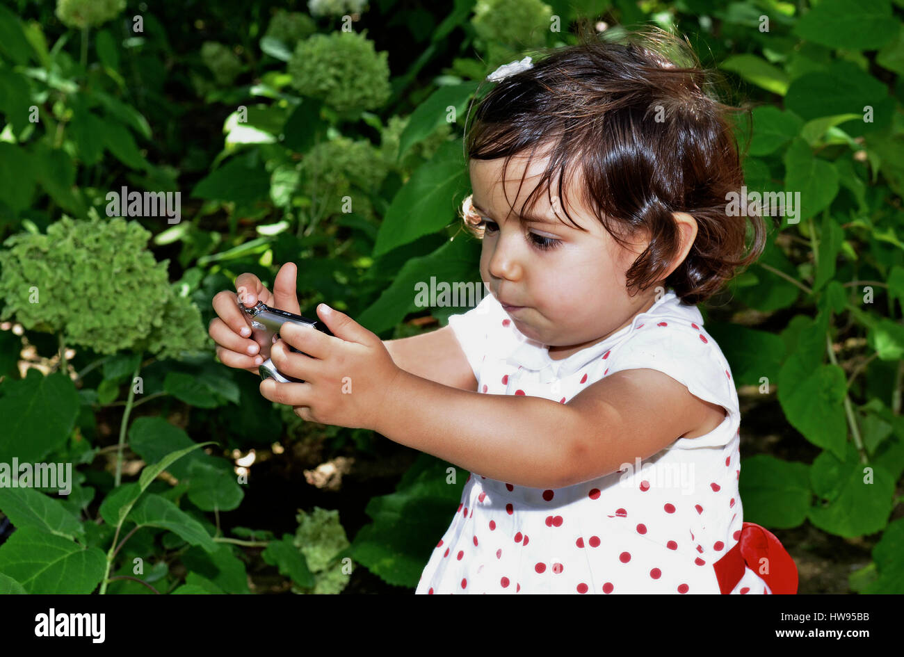 Bébé fille 3 ans essayant de tirer sur un appareil photo avec des expressions drôles Banque D'Images