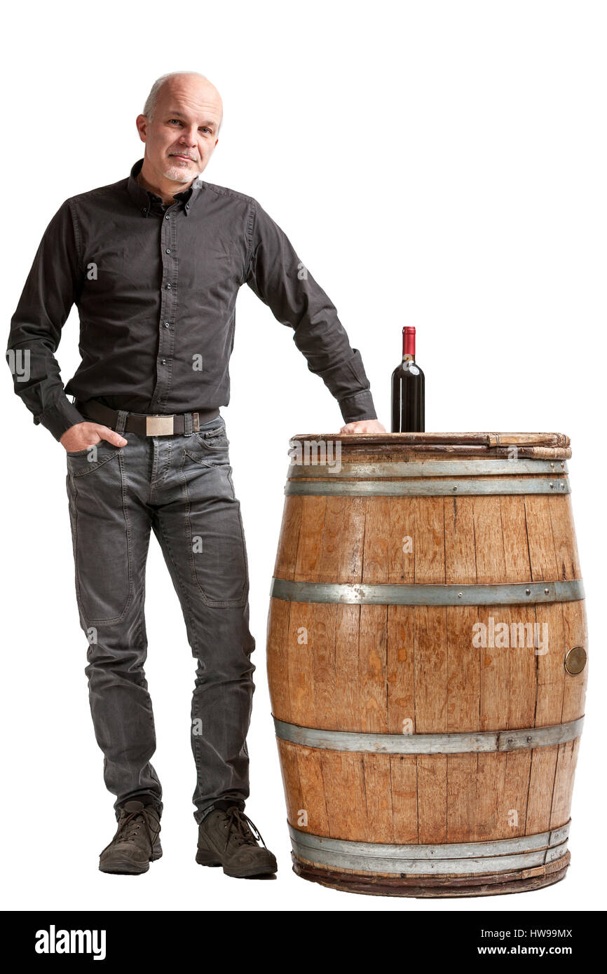 Concept de la viticulture avec un homme debout avec sa main sur un fût de chêne ou un canon avec une bouteille de vin rouge en haut isolated over white Banque D'Images