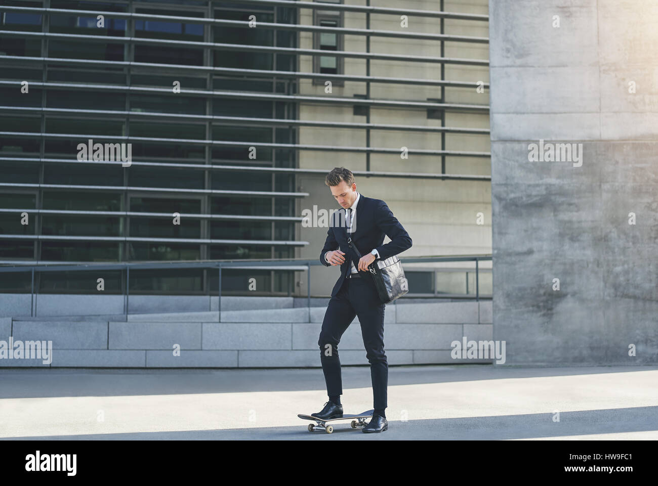 Vue frontale d'un businessman adjusting son sac en se tenant sur le skateboard Banque D'Images
