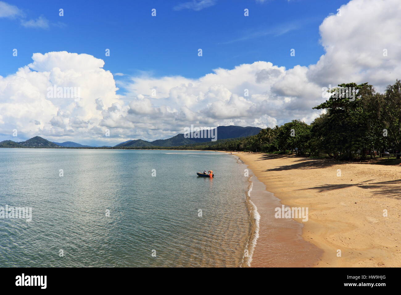 Palm Cove beach à laidback le dimanche après-midi avec des arbres jetant des ombres sur le sable et nuages reflétant sur l'eau Banque D'Images