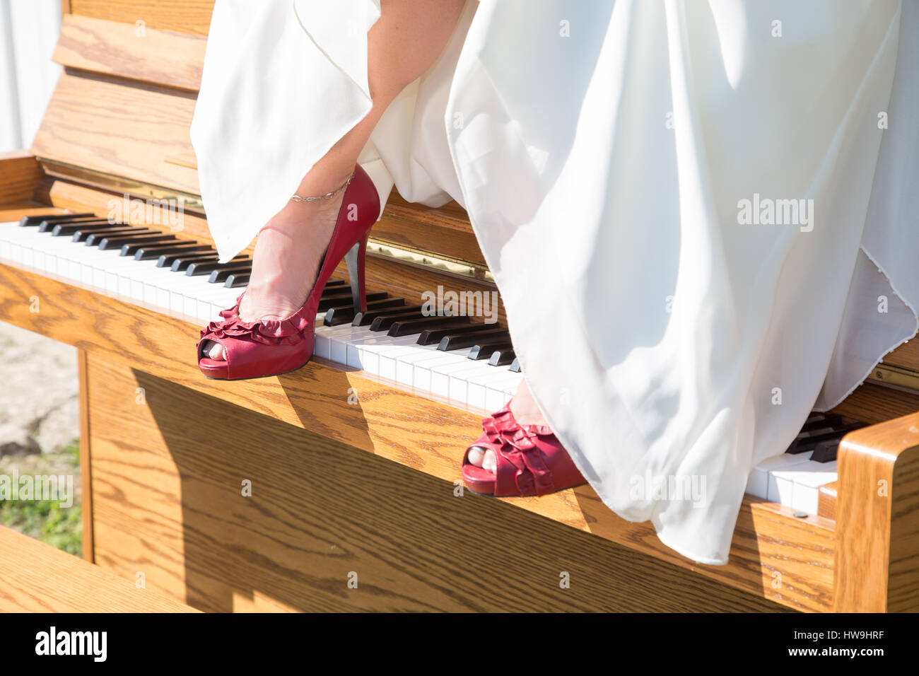 Une brides chaussures rouges reste sur les touches d'un piano qui se trouve à l'extérieur au soleil Banque D'Images