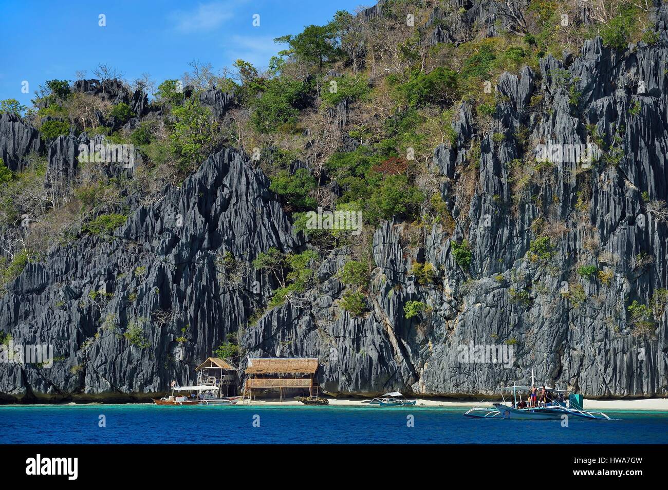 Philippines, Îles Calamian dans le nord de Palawan, l'Île Coron, zone biotique naturel et pirogue plage sous murs géants de falaises calcaires Banque D'Images