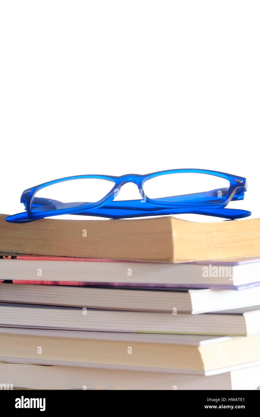 Lunettes bleues reposant sur une pile de livres et de magazines Banque D'Images