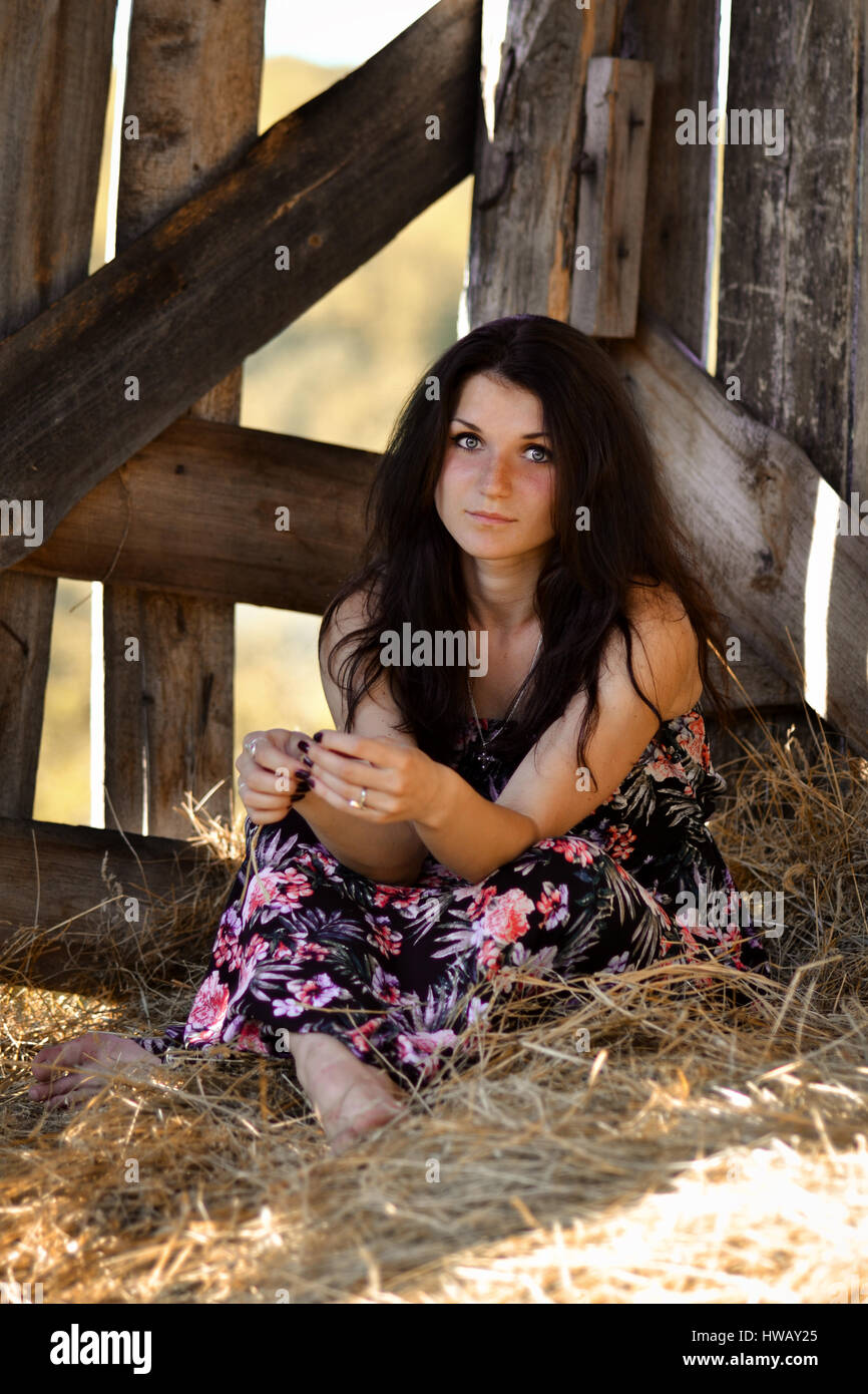 Beautiful Girl sitting in the Hay.jolie fille avec hay.Gorgeous woman,fille dans le sol en bois stable stable,jaune,sec,de,botte de foin pile.Belle Banque D'Images