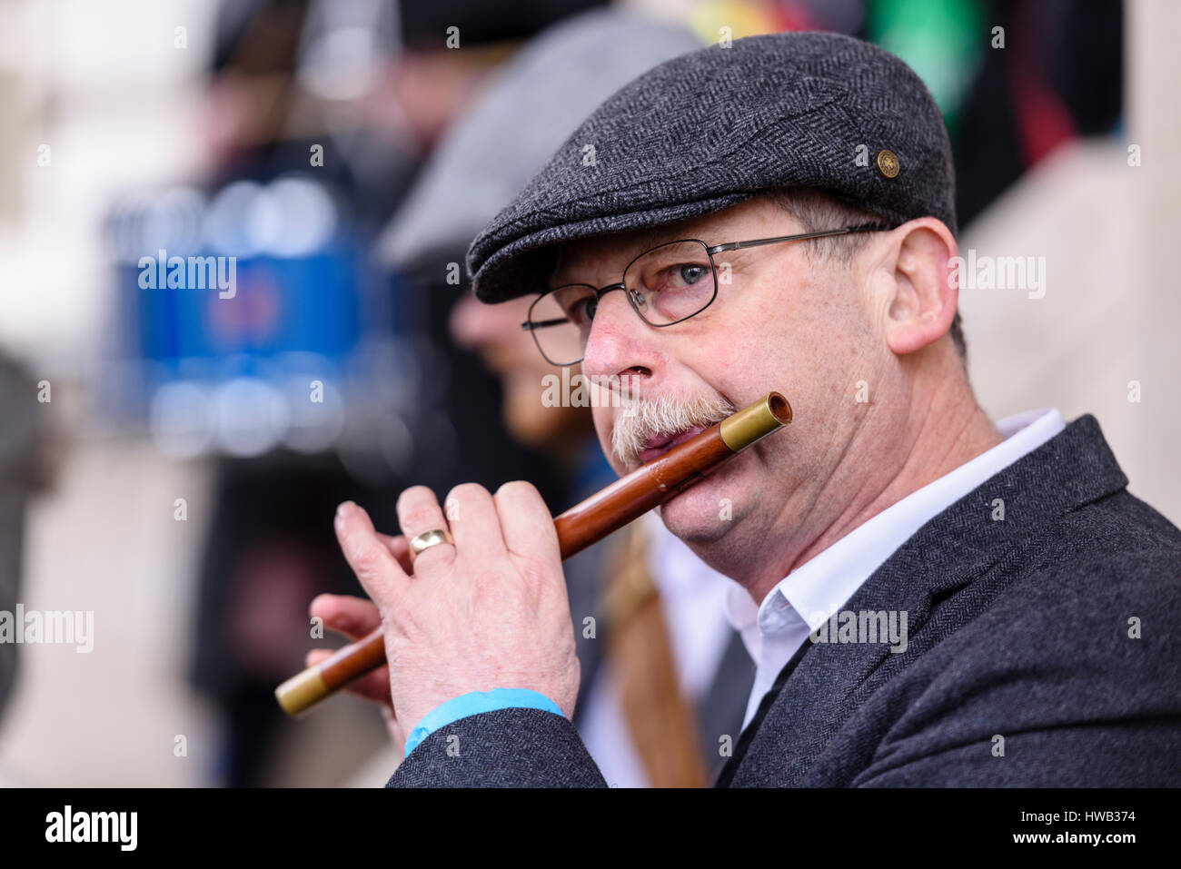 Un homme avec une moustache, et portant un capuchon plat tweed joue un flûte traversière irlandaise traditionnelle. Banque D'Images