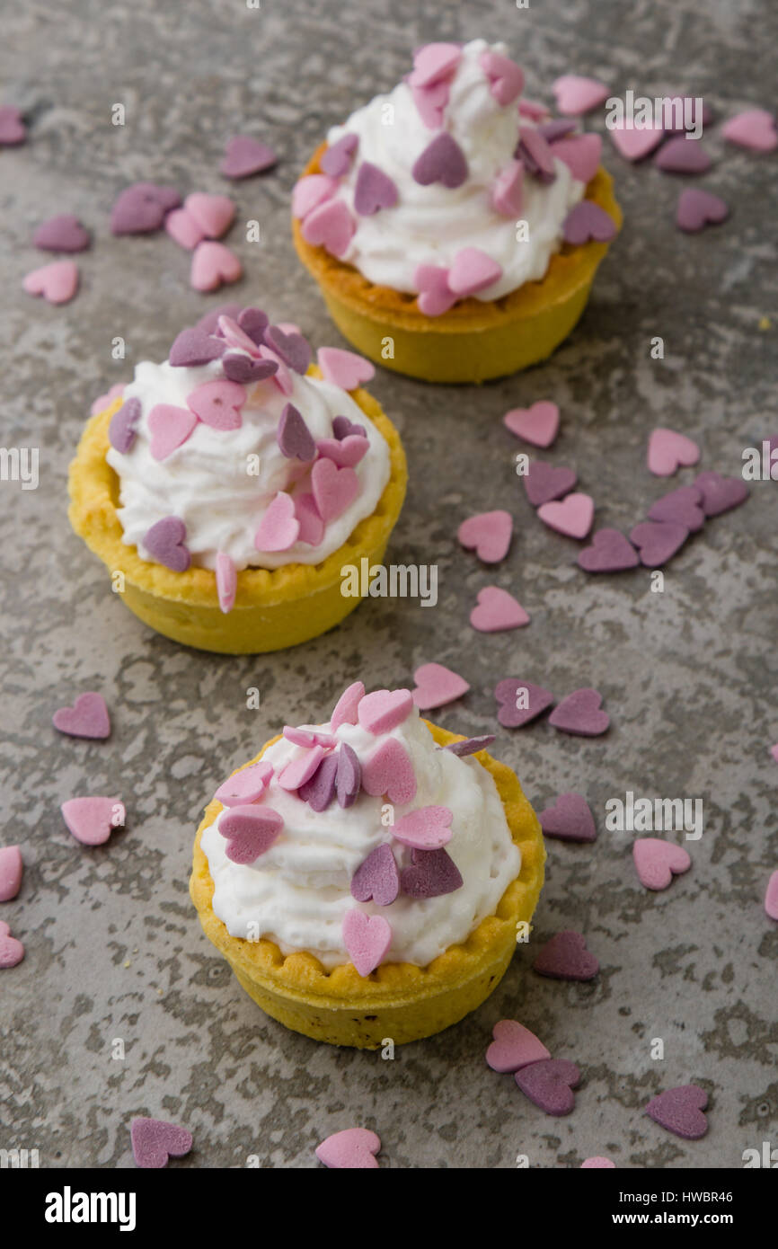 Mini tarte avec crème fouettée et ornement coeur rose Banque D'Images