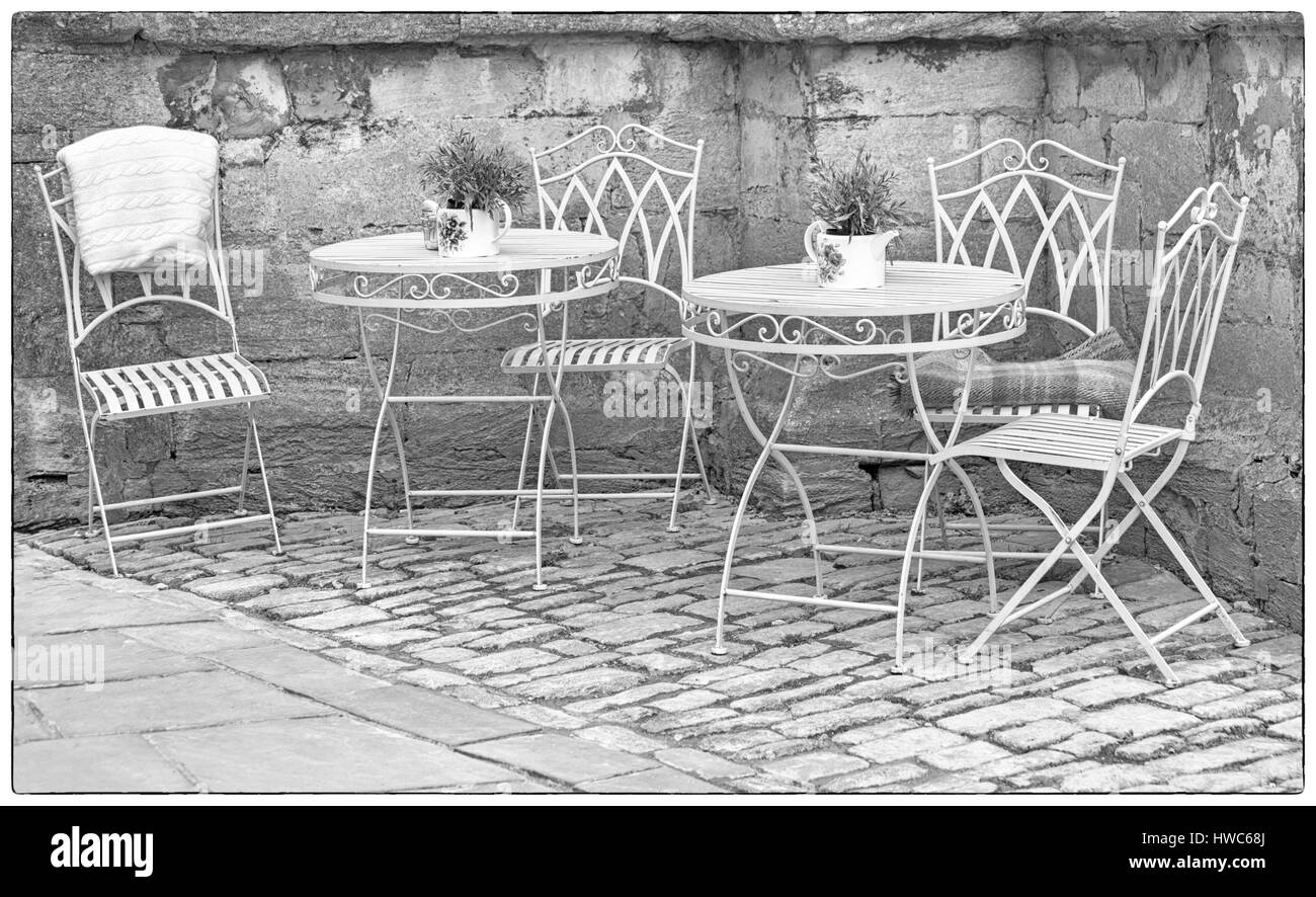 Cirencester - fer forgé orné des tables et des chaises avec des pots de plantes dans un coin de Cirencester, Gloucestershire en Mars Banque D'Images