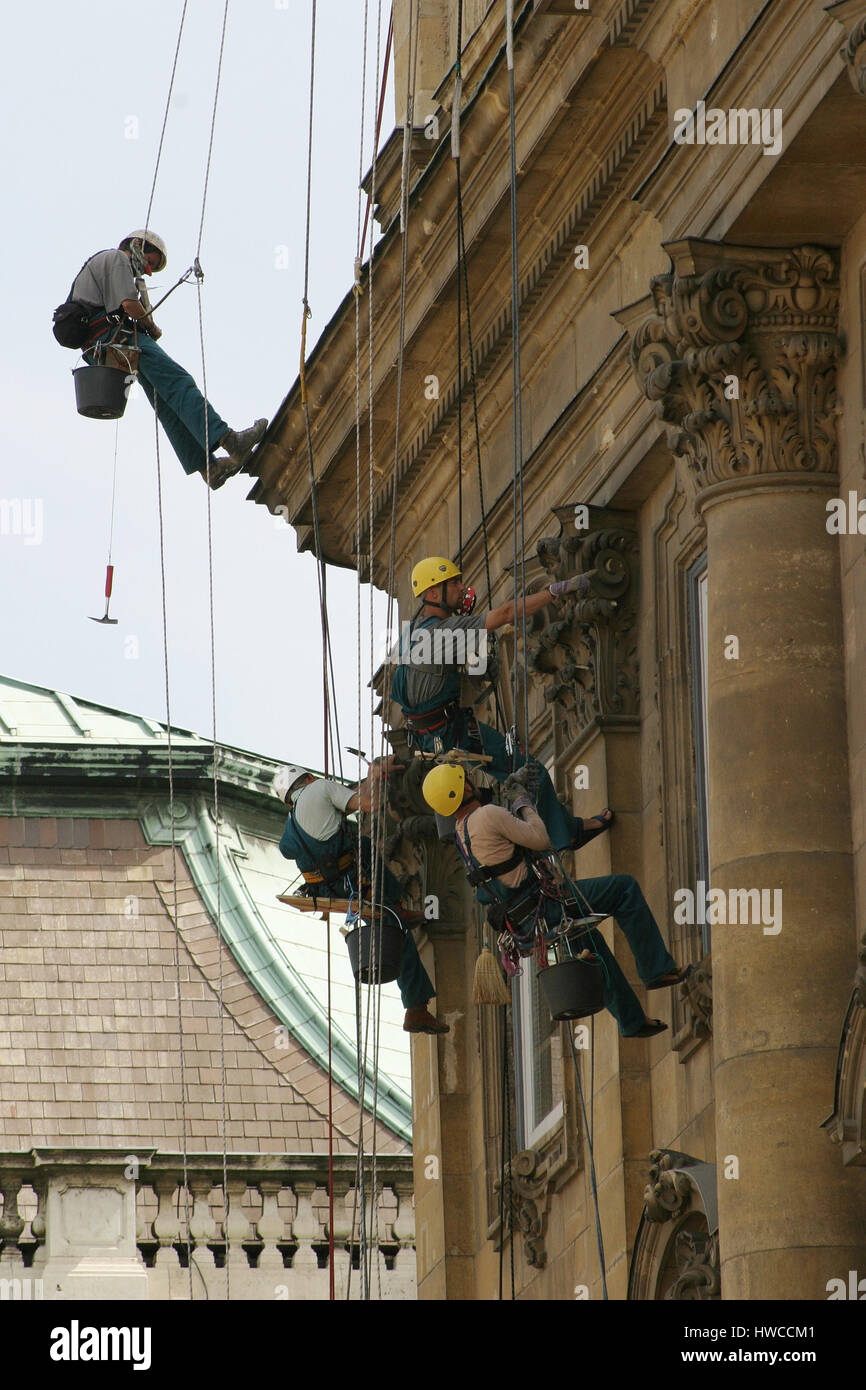 Tailleurs sur des cordes et harnais de la restauration et la réparation de maçonnerie sur une façade à Budapest, Hongrie. Banque D'Images