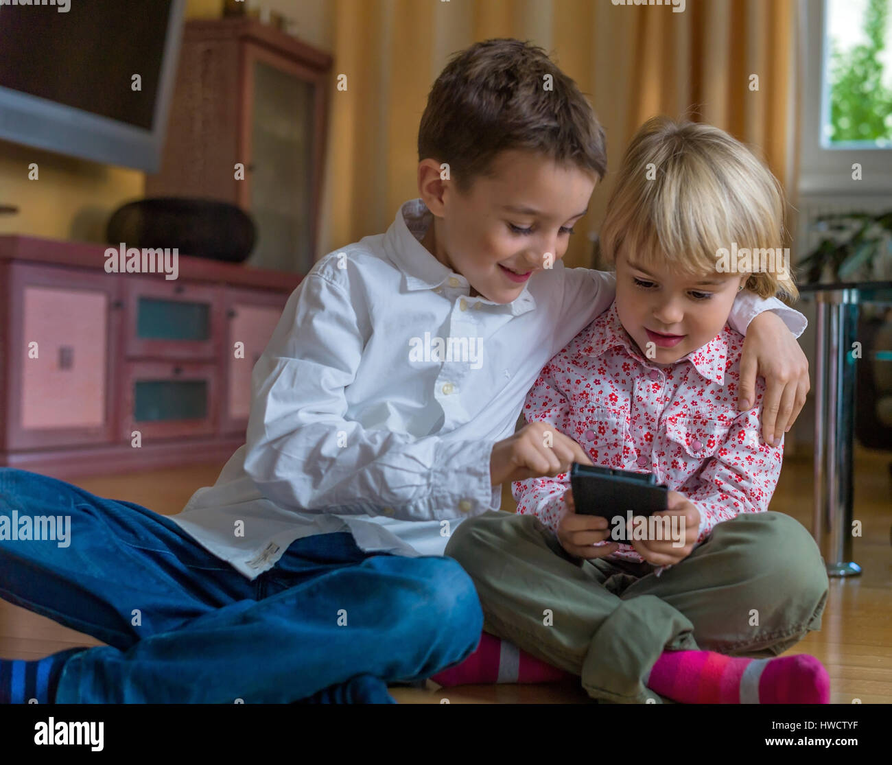 Un enfant joue avec un téléphone mobile. Téléphone mobile pour enfants, Ein genre spielt mit la main. Mobiltelefon für Kinder Banque D'Images