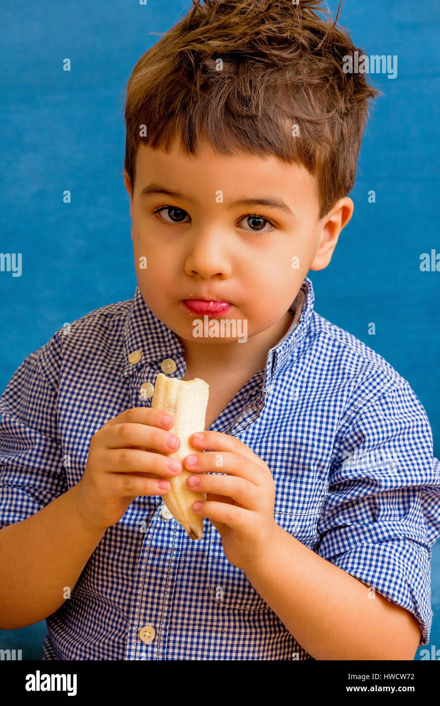 Un petit garçon mange une banane. Photo symbolique de l'alimentation, de l'ein kleiner Junge isst eine Banane. Symbolfoto für Ernährung Banque D'Images