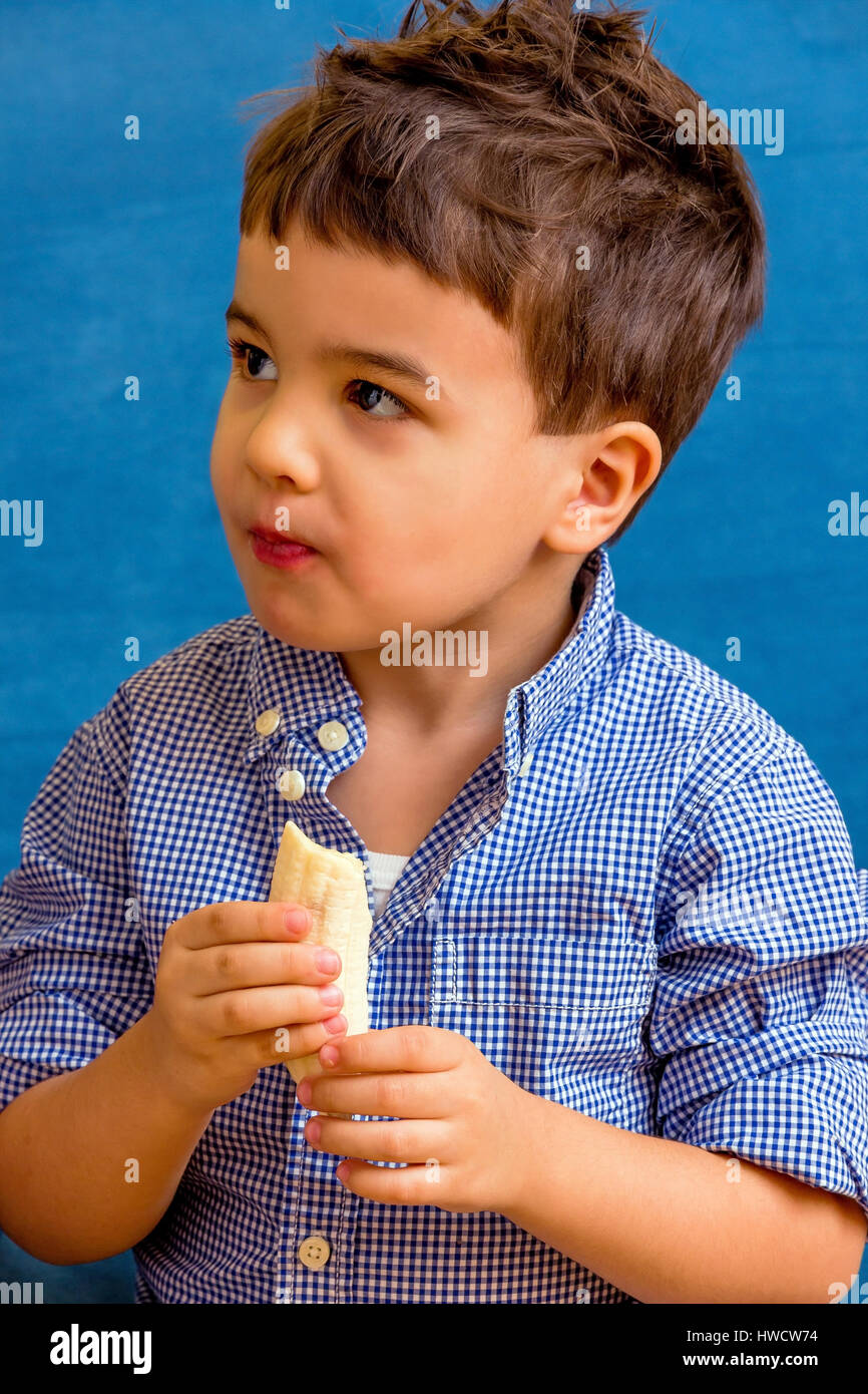 Un petit garçon mange une banane. Photo symbolique de l'alimentation, de l'ein kleiner Junge isst eine Banane. Symbolfoto für Ernährung Banque D'Images