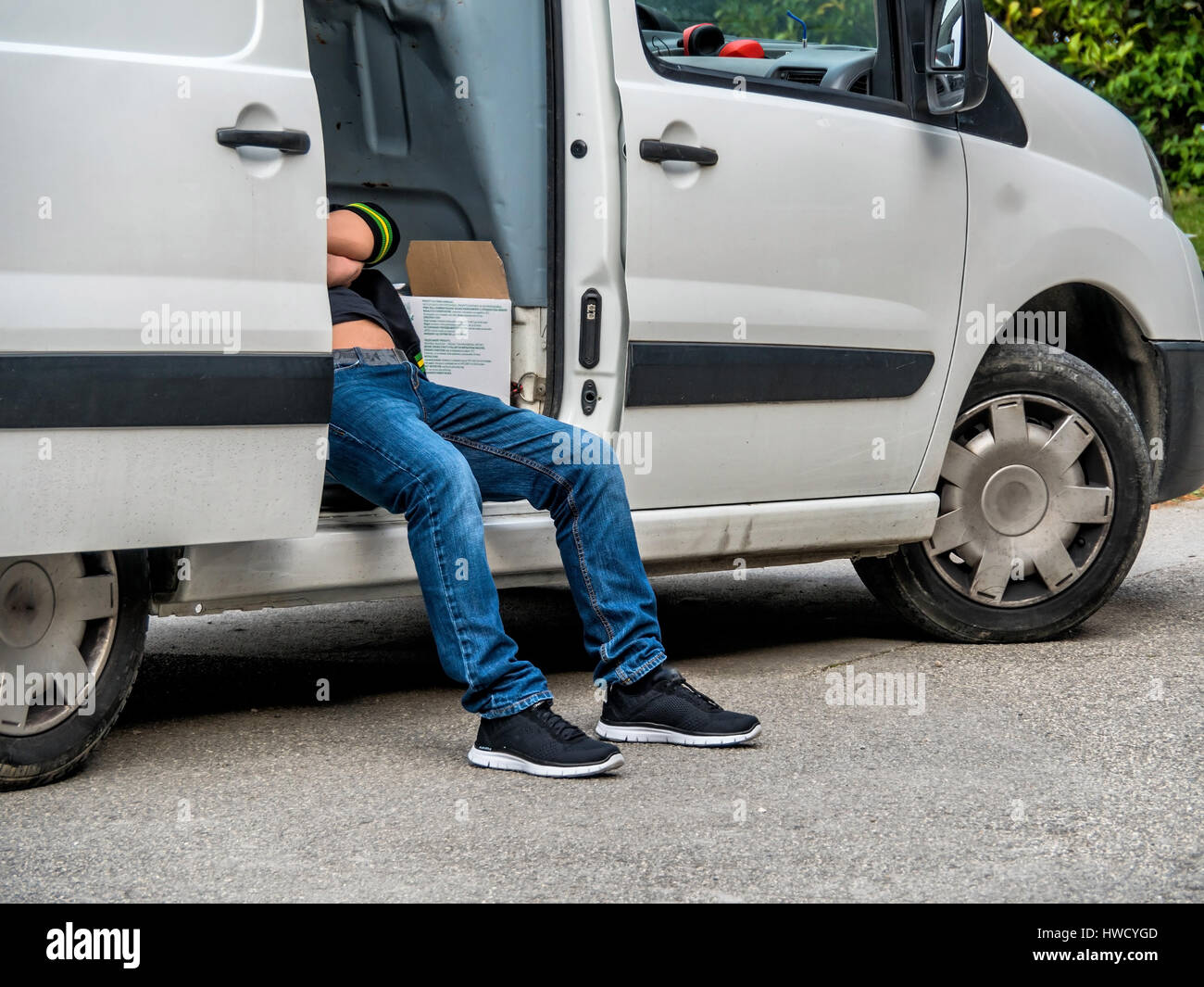 Le conducteur d'un fournisseur effectue la livraison des colis avec une pause, Der Fahrer von Lieferfirma macht bei der Auslieferung von Paketen eine Pause Banque D'Images