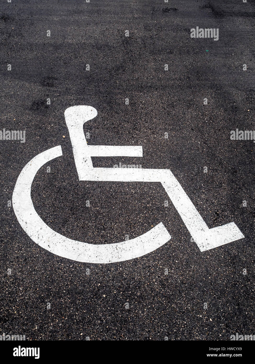 Un fauteuil roulant est à droite sur une place de stationnement pour personnes à mobilité réduite., Ein Rollstuhl ist auf einem Parkplatz für behinderte angebracht. Banque D'Images