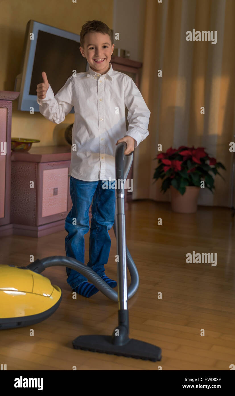 Un garçon suce un salon avec un aspirateur. Les enfants avec le nettoyage, Ein Bub saugt mit einem Staubsauger ein Wohnzimmer. Kinder beim Putzen Banque D'Images