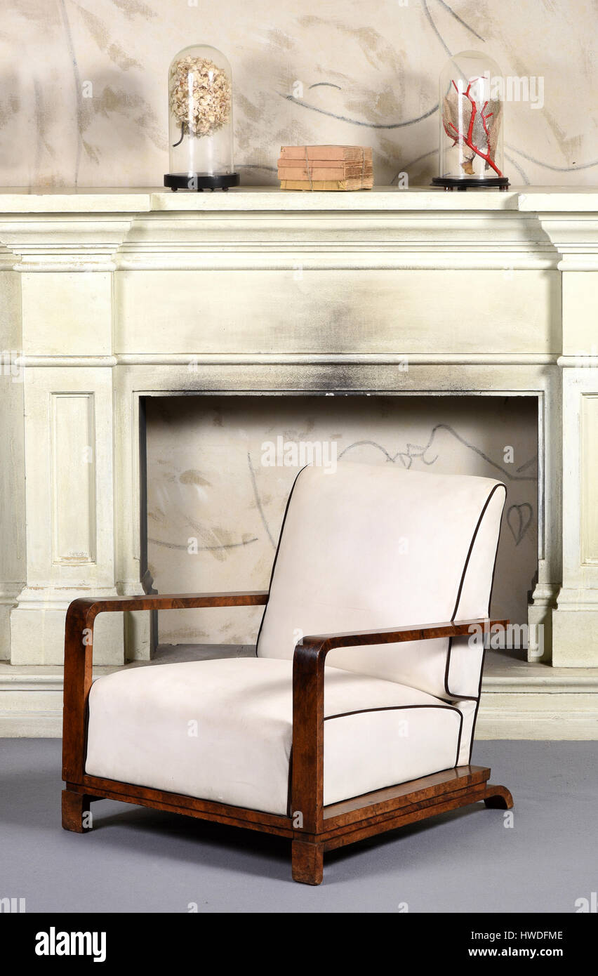 Style Art déco meubles blanc fauteuil avec accoudoirs en bois angulaire typique et faible en bandoulière design en face d'une vieille cheminée de fumée Banque D'Images