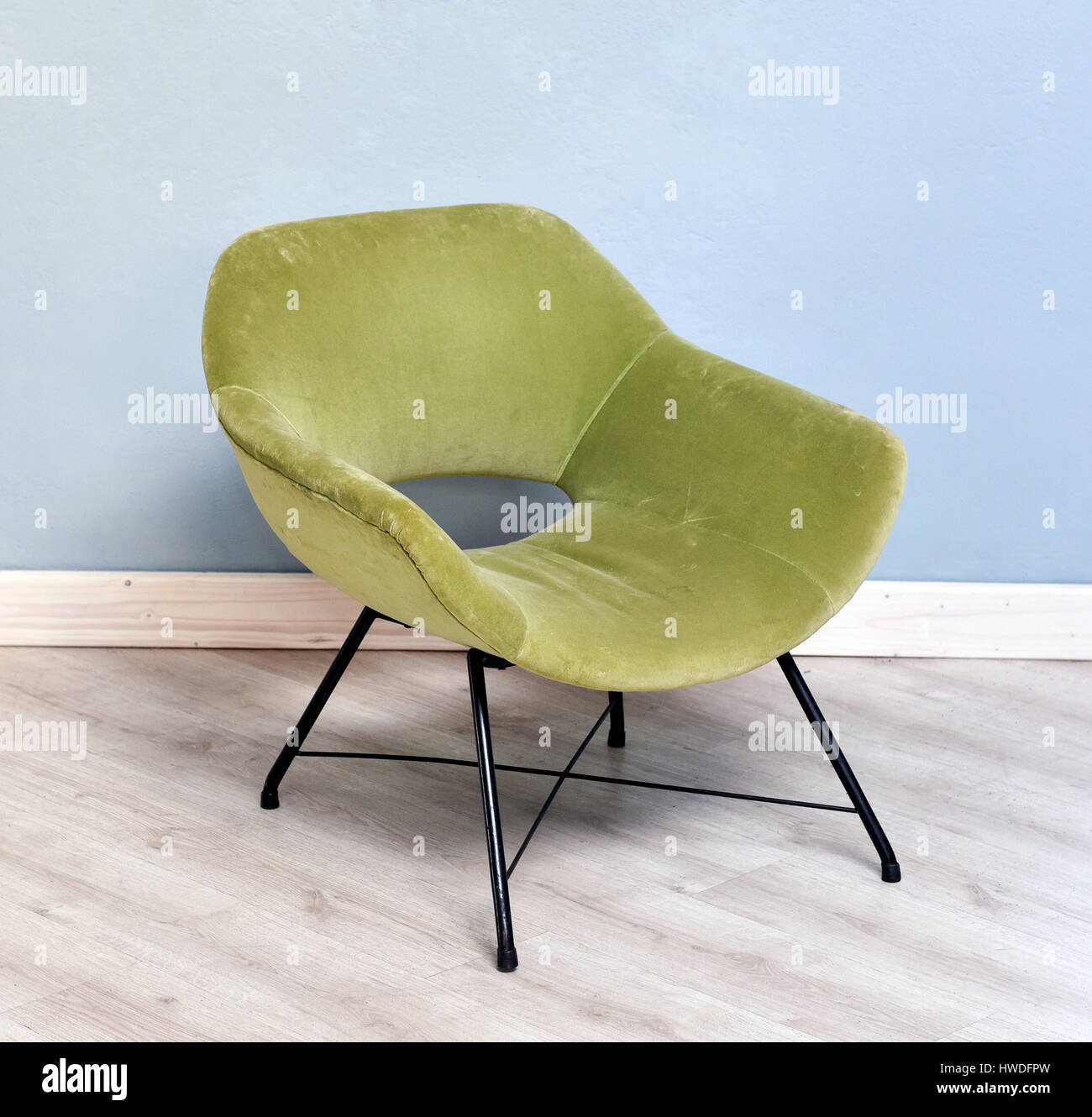 La vie des petits meubles rétro encore velours vert Plush Fauteuil inclinable avec pieds en métal noir dans la chambre avec plancher de bois et mur bleu clair Banque D'Images